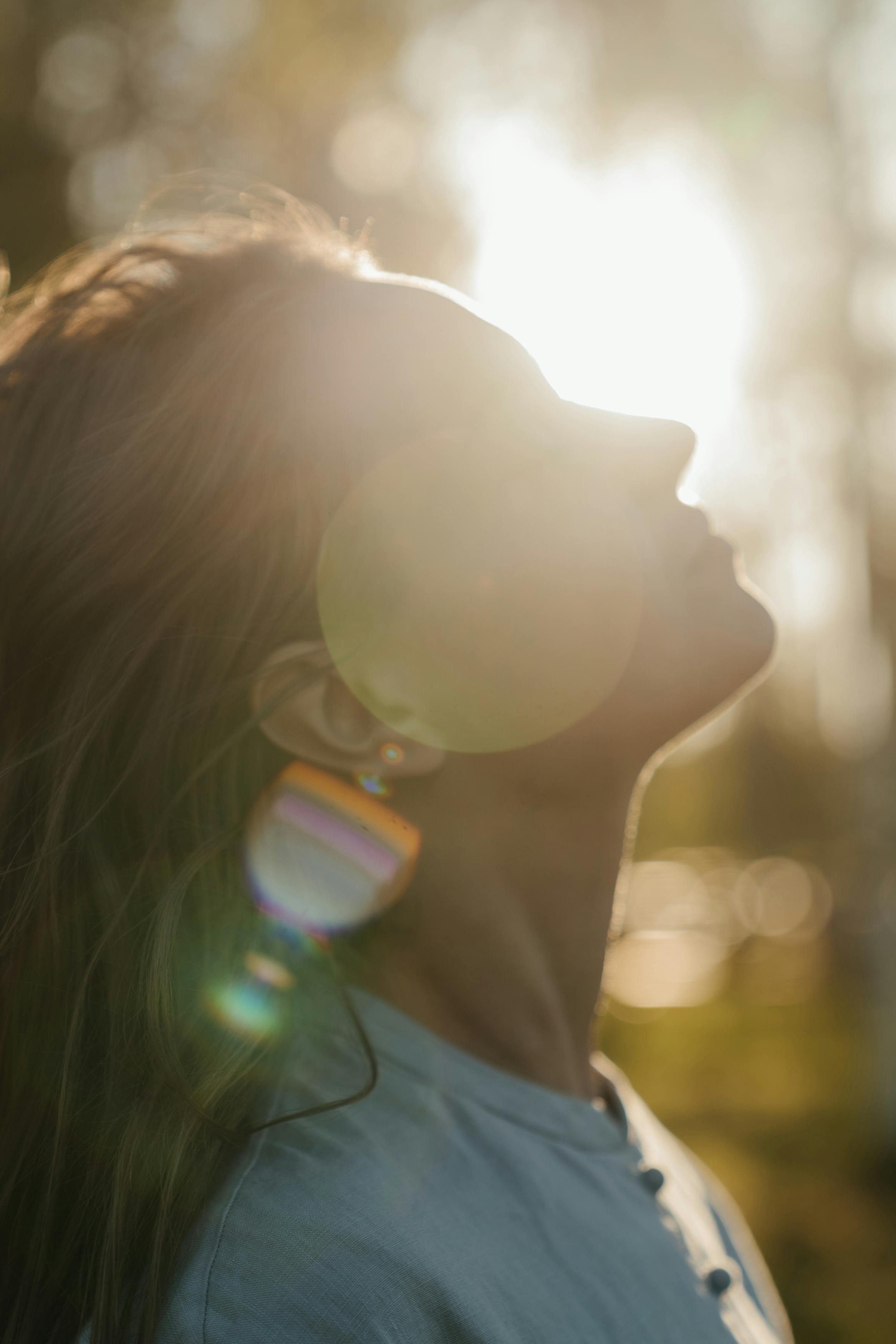 Mulher na natureza, de perfil, com luz natural suave na cara